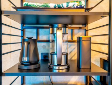 Modern kitchen shelf with a black electric kettle, a glass coffee maker, and a metal canister at Bayside Villa Miyako Iland.