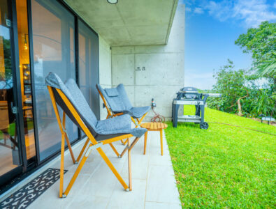 Outdoor patio with comfortable chairs and a barbecue grill overlooking the garden at Bayside Villa Miyako Iland.