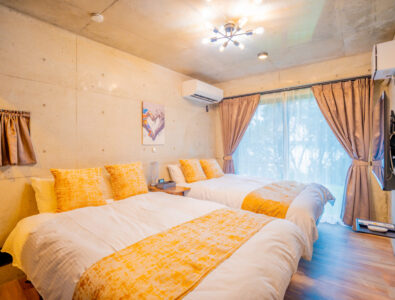 Cozy bedroom with two double beds, yellow accents, and large window at Bayside Villa Miyako Iland.