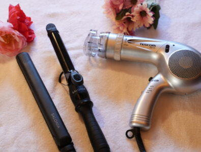 Hair styling tools including hairdryer, straightener, and curling iron, arranged with flowers at Enishiya Izumo.