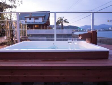 Outdoor jacuzzi on the terrace with scenic evening view at Ocean Villa Naruto, offering a relaxing bath experience.