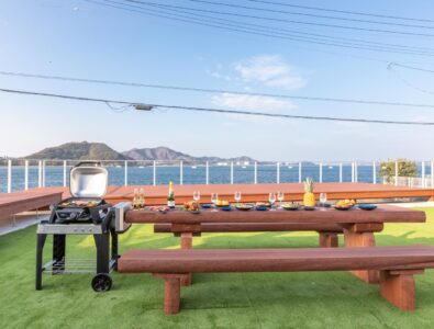 Seaside barbecue area with picnic tables and grill at Ocean Villa Naruto, offering stunning ocean views.