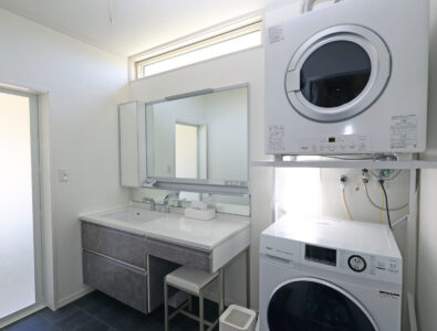 Laundry area with washing machine, dryer, and modern sink at Ocean Villa Tokunoshima.