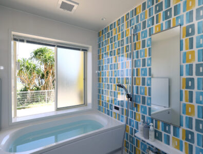 Modern bathroom with colorful tile wall, bathtub, and large window at Ocean Villa Tokunoshima.