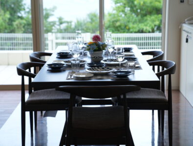 Elegant dining table set with plates, glasses, and floral centerpiece, overlooking a garden at Ocean Villa Tokunoshima.