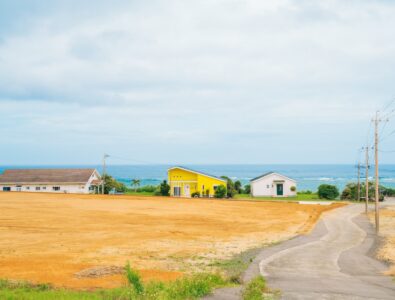 Scenic ocean view with a yellow villa and neighboring houses at Ocean Villa Tokunoshima.